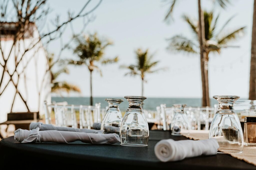 Elegant seaside outdoor dining setup with glassware and ocean view, ideal for luxury events.